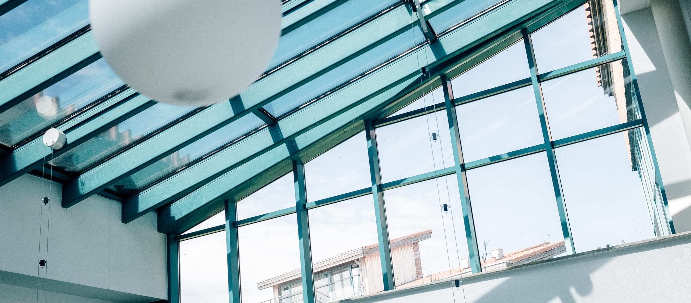 Innenansicht des Klinikgebäudes mit schrägem Glasdach und Fenstern darunter.