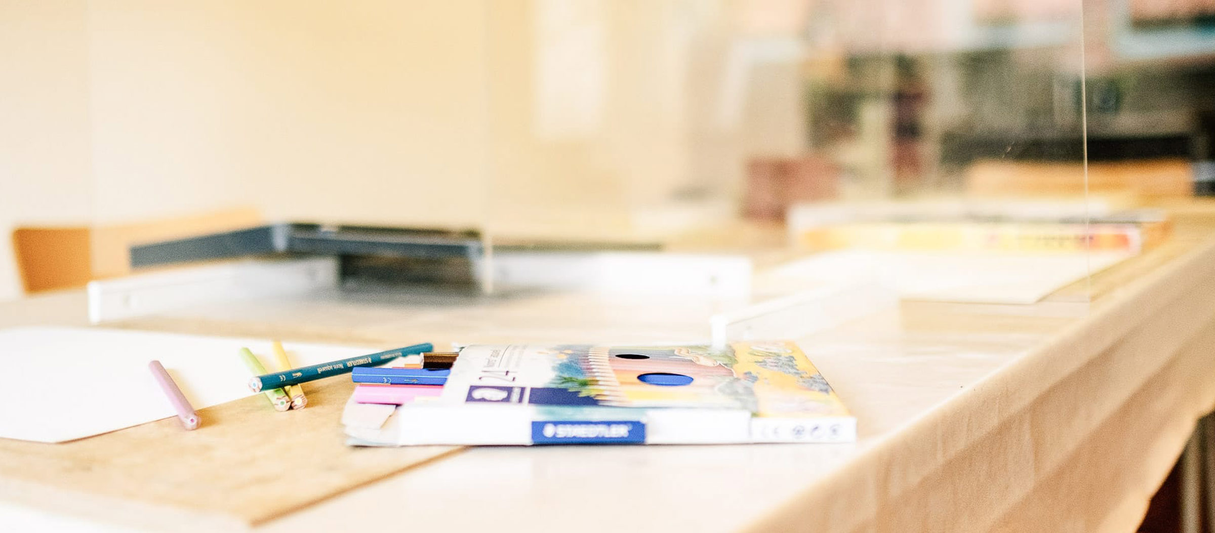 Ein Packung mit Buntstiften auf einem mit Papier bedecktem Tisch.