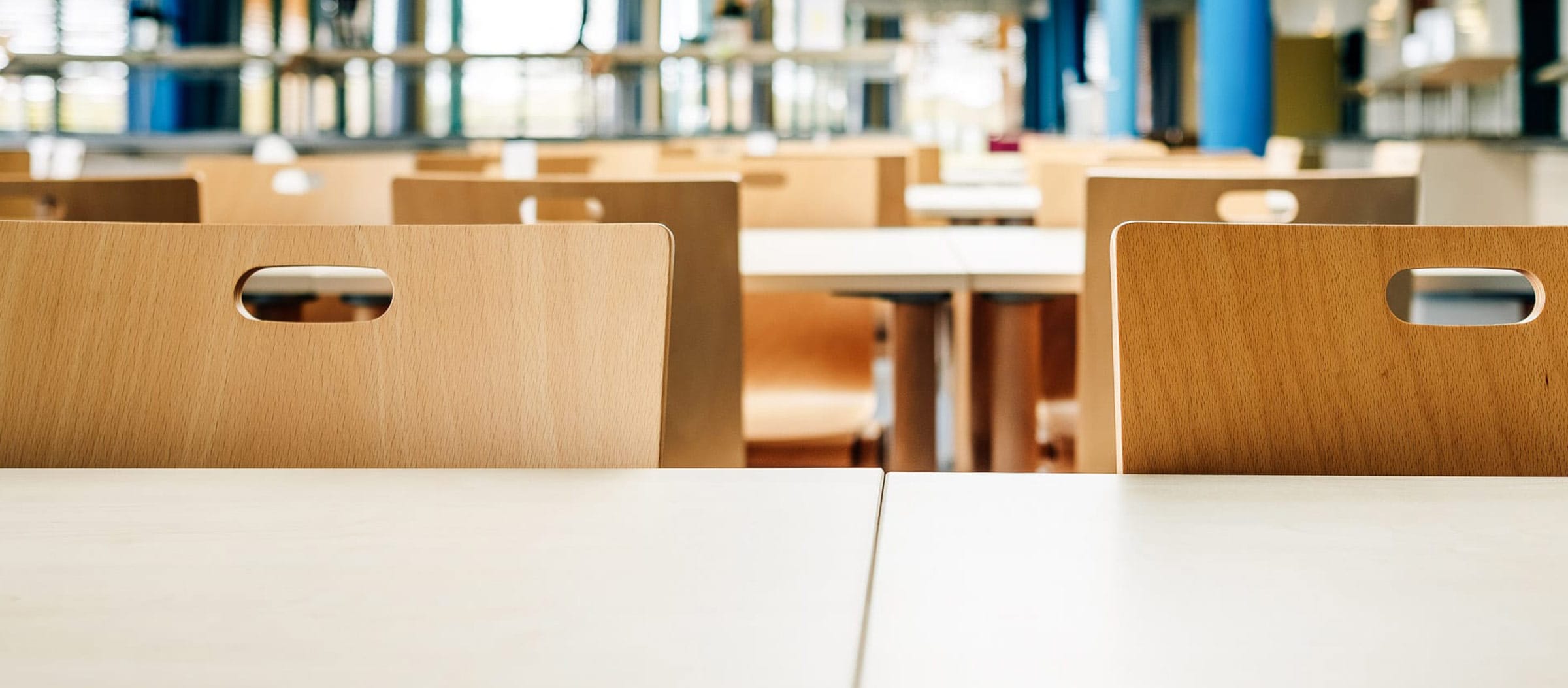 Weiße Tische und helle Holzstühle im hellen Speisesaal.
