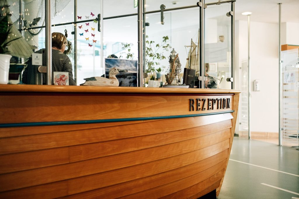 Die hölzerne Rezeption der Ostseeklinik in Form eines Schiffsbugs, auf dem Rezeption steht.