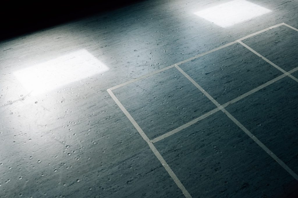 Dunkler, glänzender Boden mit weißem Raster und zwei rechteckigen Lichtreflexionen.