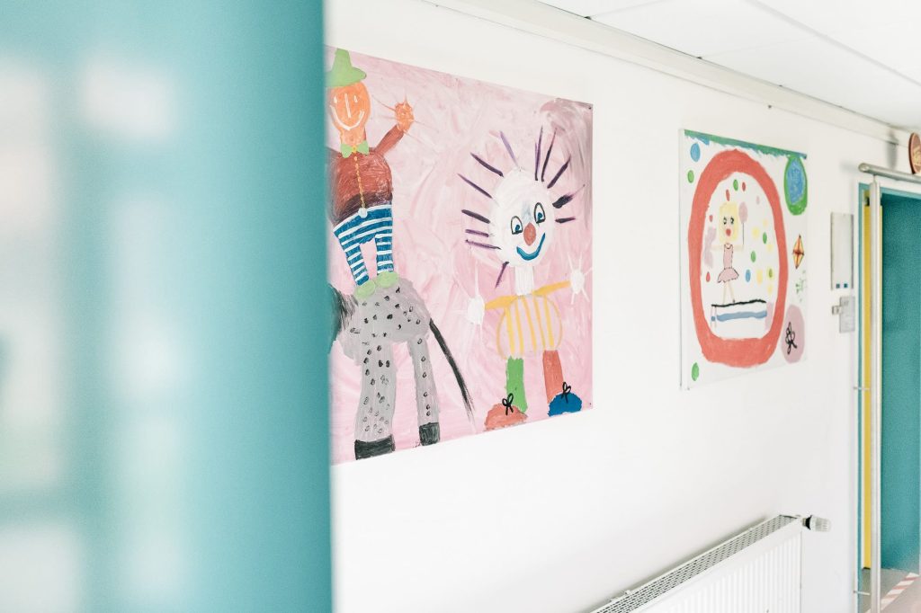 Heller Flur der Klinik mit bunten, von Kindern gemalten Bildern.