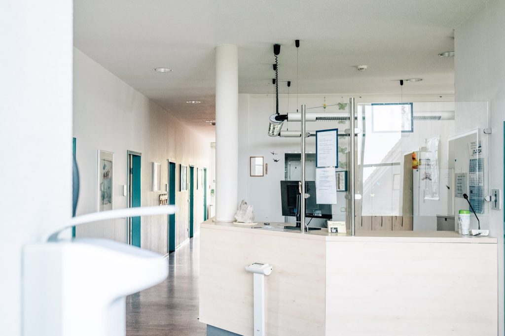 Der helle Flur einer Station der Ostseeklinik Zingst: links Zimmertüren, rechts die Rezeption vor dem Stationszimmer.
