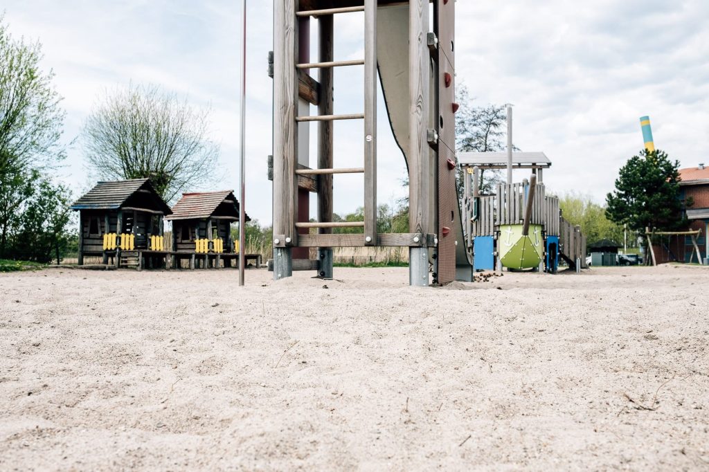 Kinderspielplatz mit Holz-Klettergerüsten auf hellem Sandboden.